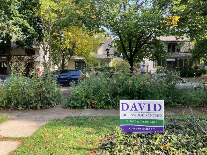 A David Greenwood-Sanchez yard sign in a lush garden